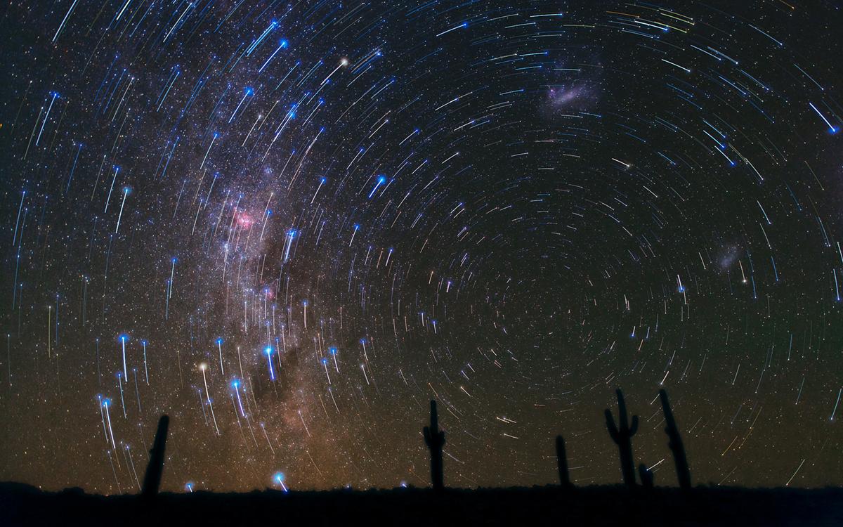 This  gorgeous photograph, taken in the Atacama Desert in Chile, shows star  trails circling the South Celestial Pole, over a cacti-dominated still  landscape. The star trails show the apparent path of the stars in the  sky as the Earth slowly rotates, and are captured by taking  long-exposure shots. A  final deeper exposure was superimposed over the magnificent trails,  revealing many more, fainter stars and, just rising above the horizon,  the southern Milky Way, with its patches of dark dust and the well-known  pinkish glow of the Carina Nebula. Towards the right, the satellite  galaxies of the Milky Way, the Large (top-centre) and Small  (bottom-right) Magellanic Clouds, can also be seen.